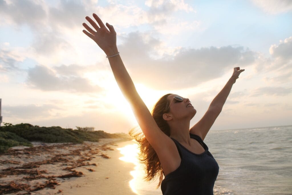 Vrouw op het strand die zich vrij voelt na een Transformatie Sessie